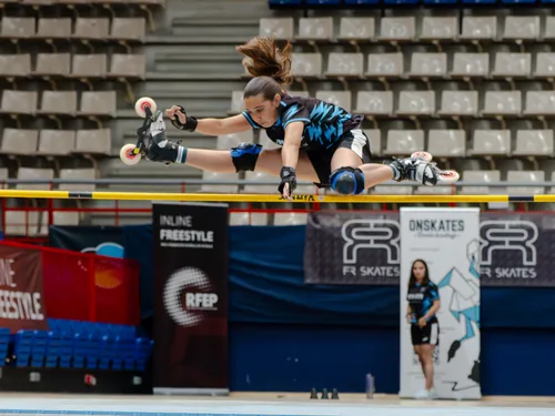 Patinadora del Team Onskates saltando una valla con las piernas extendidas en spagat