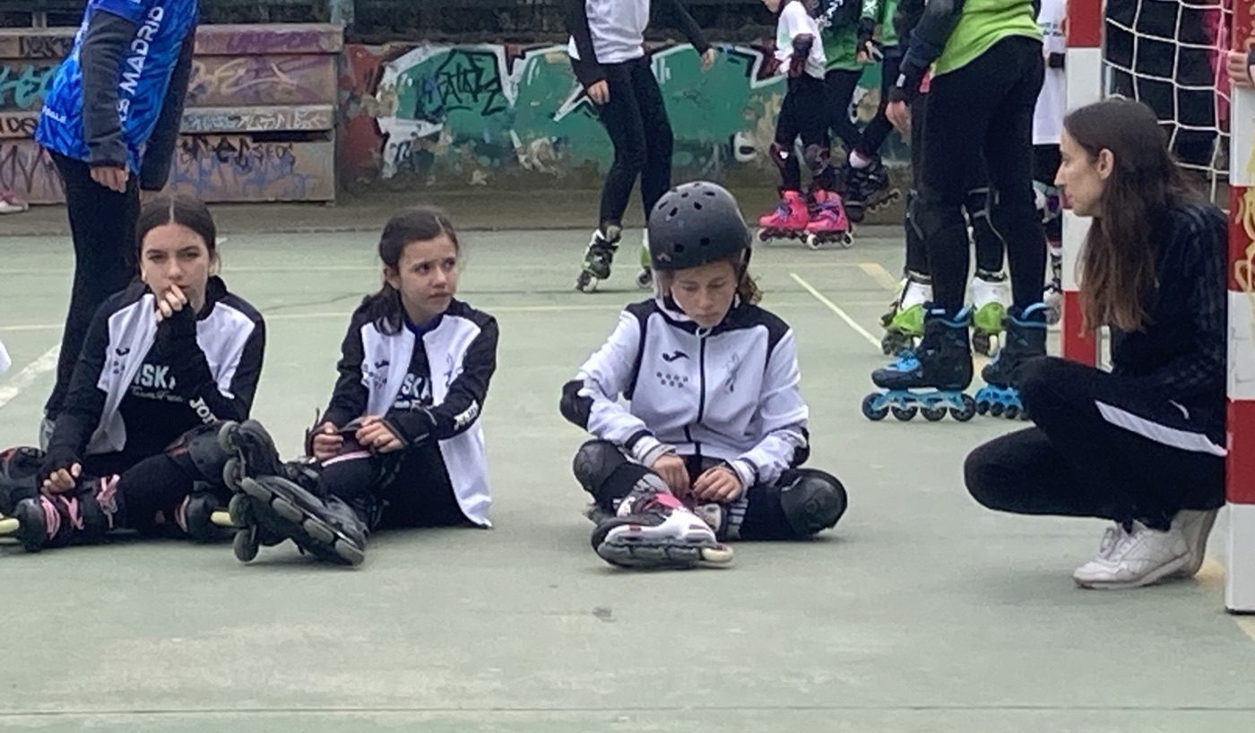Alumnas de la Escuela Onskates ajustándose casco, rodilleras y muñequeras antes de patinar, acompañadas por su monitora